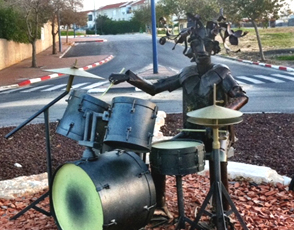 sculpture of a man playing drums made from the metal of Qassam rockets